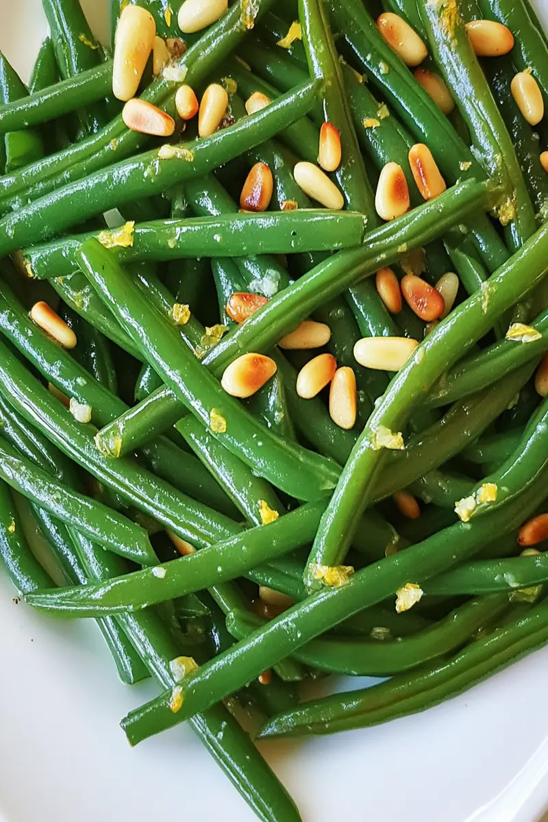 Low FODMAP Lemon Green Beans 7 Low FODMAP lemon green beans with toasted pine nuts on white serving platter, bright and fresh side dish